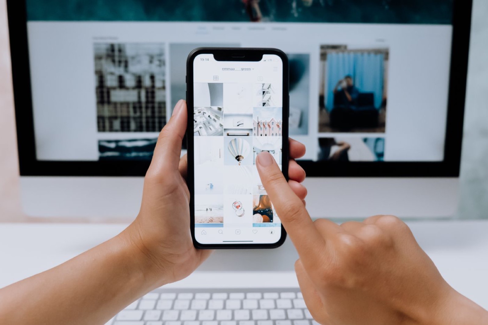 Hands tapping a photo grid on a phone, with the same grid on a monitor.