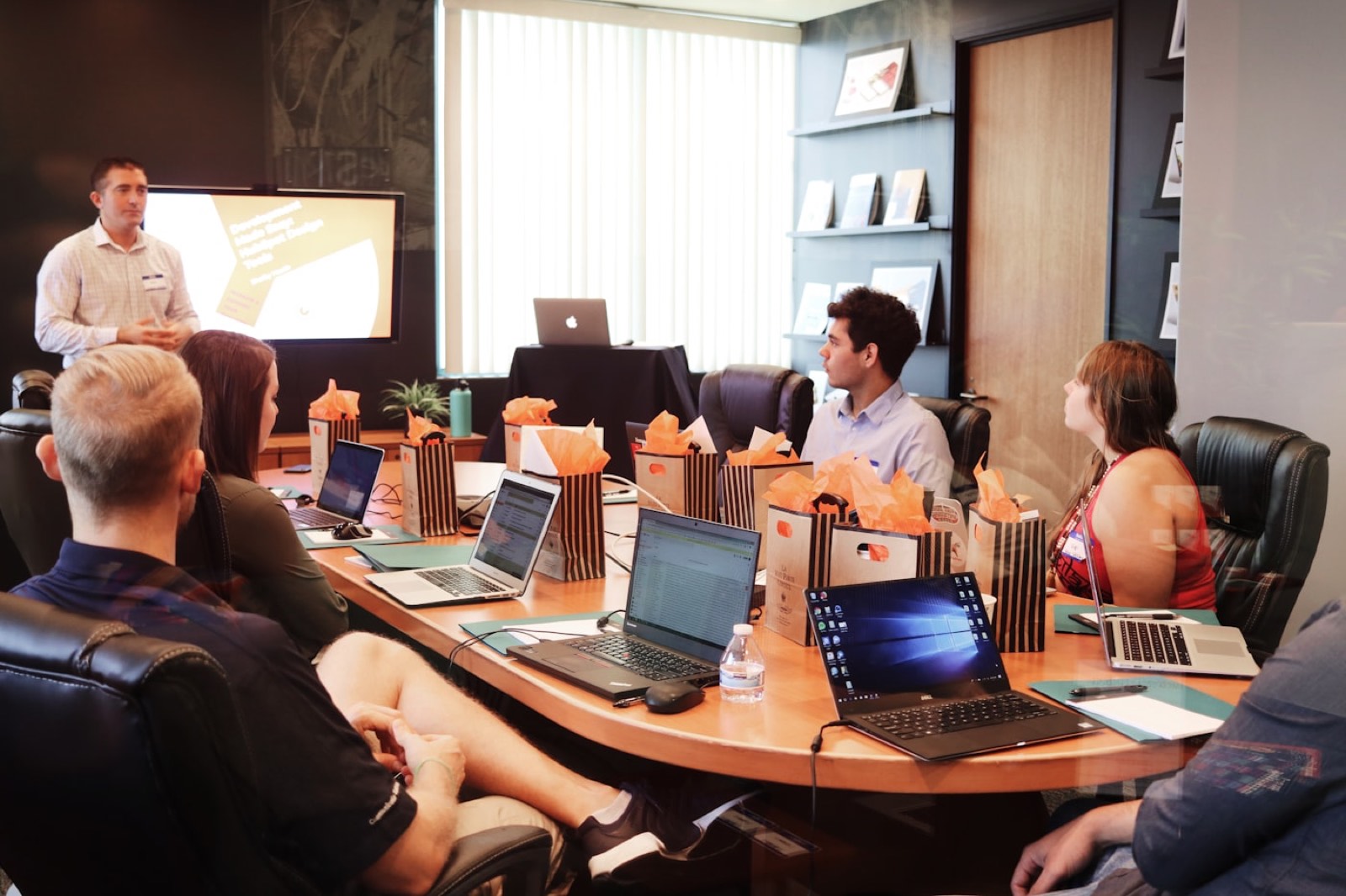 A person presenting to colleagues around a conference table.