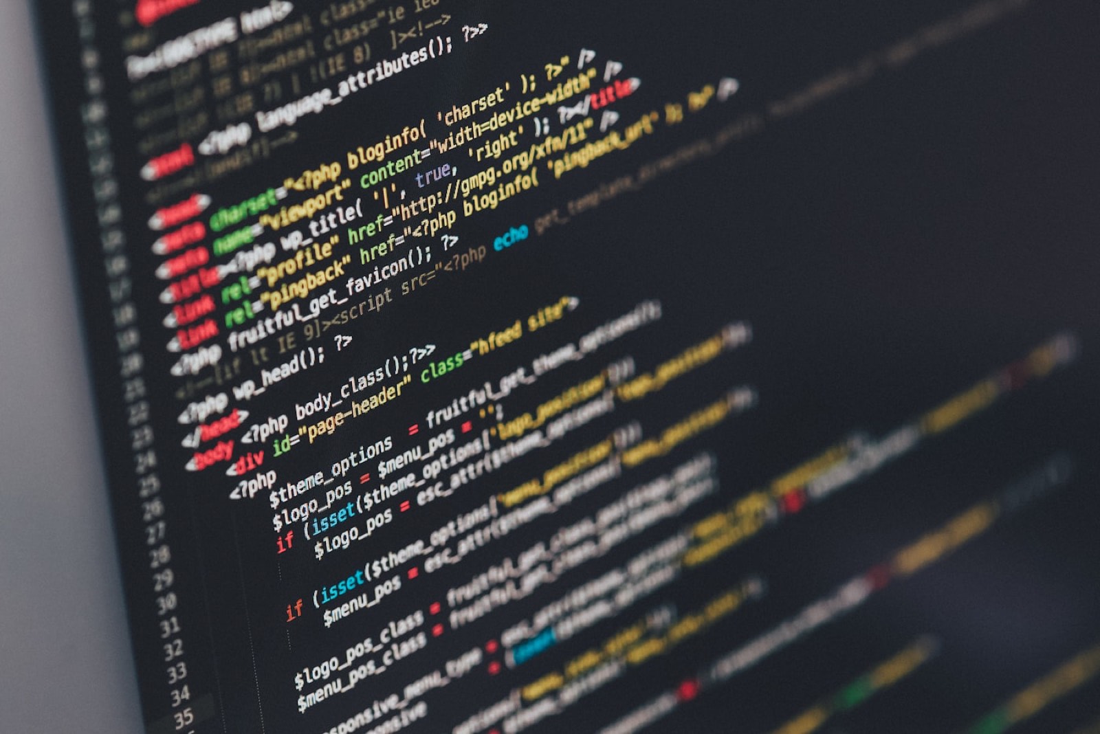 A monitor showing code in a dim workspace.