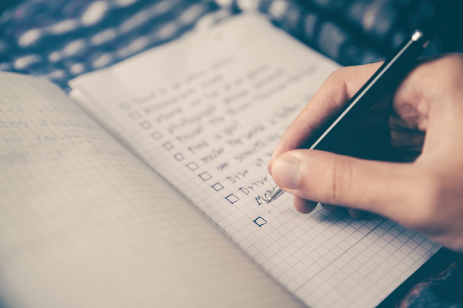 A hand checking an item off a handwritten list.