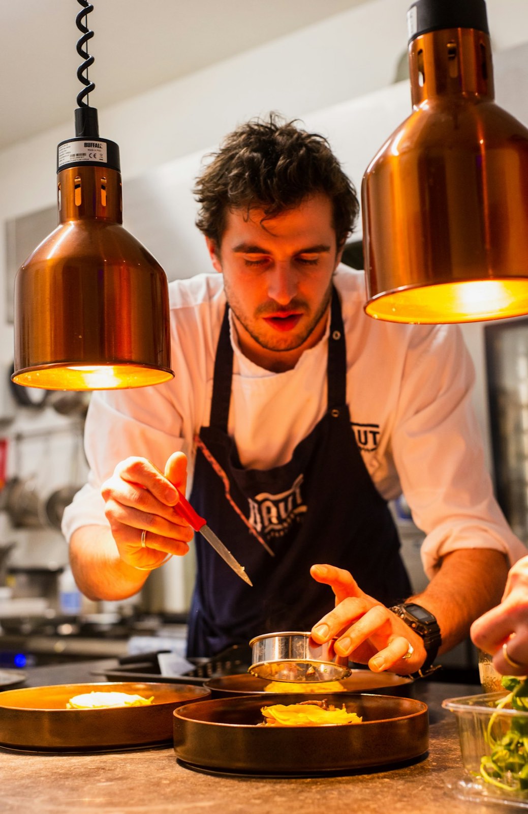 A chef plating a dish in a restaurant kitchen.