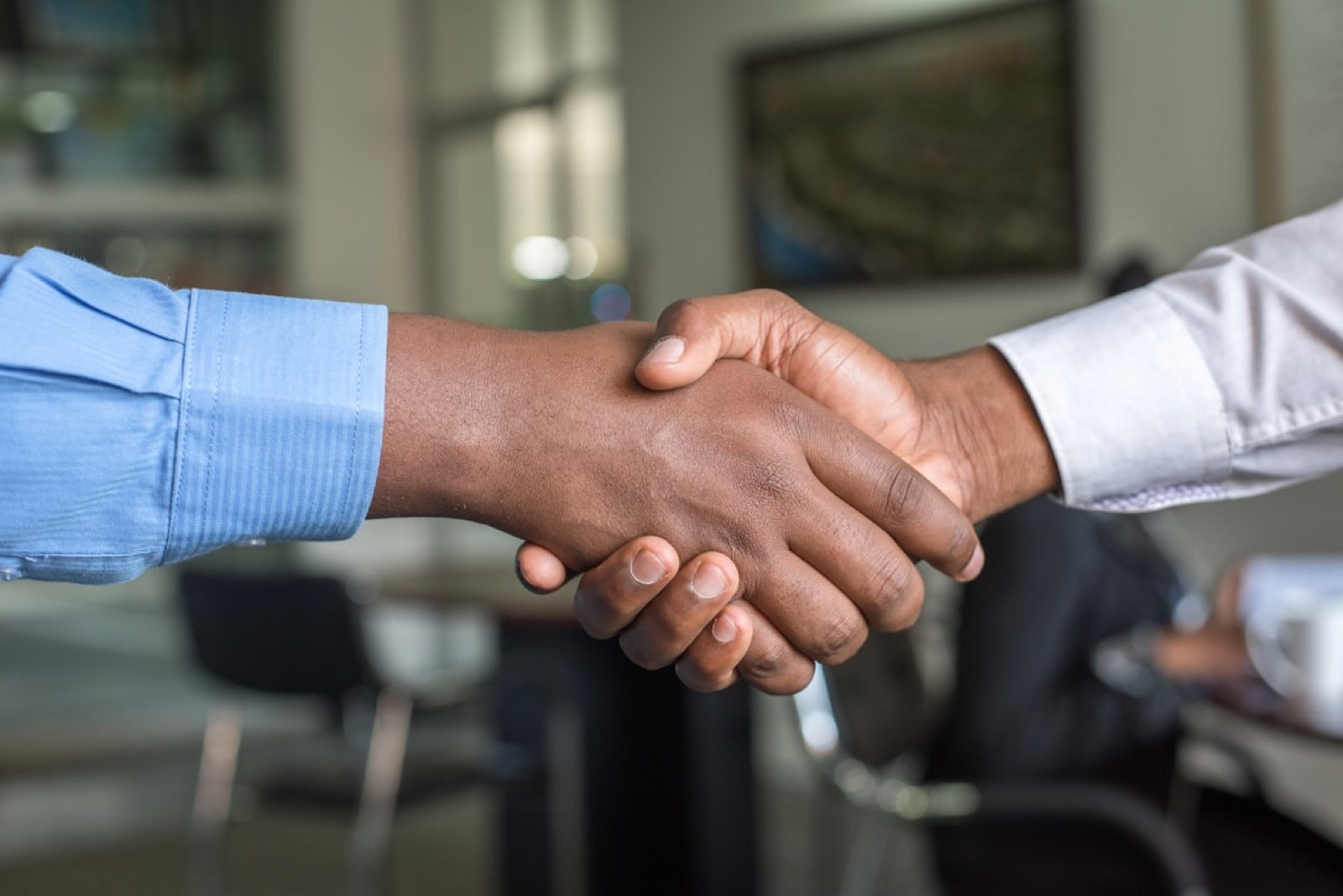 Two people shaking hands across a conference table.